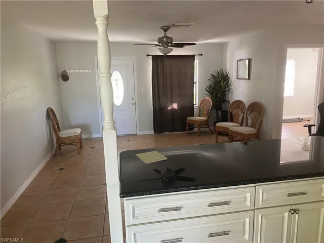 Kitchen island featuring white cabinetry with brushed nickel hardware and a dark countertop