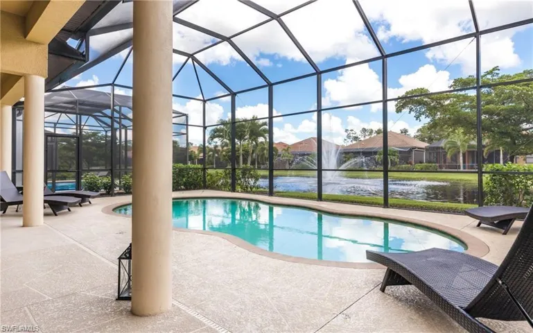Outdoor pool featuring a sunroom, a patio, glass enclosure, and a water view
