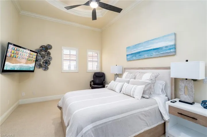 Carpeted bedroom featuring ornamental molding and a ceiling fan