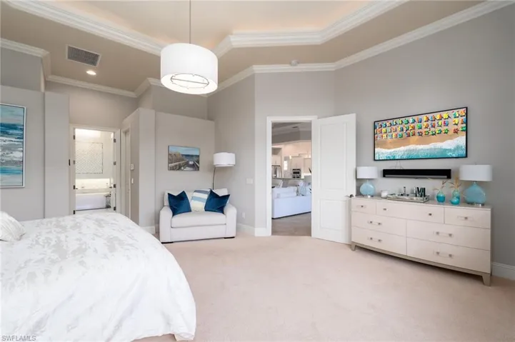 Bedroom with light colored carpet, crown molding, and connected bathroom