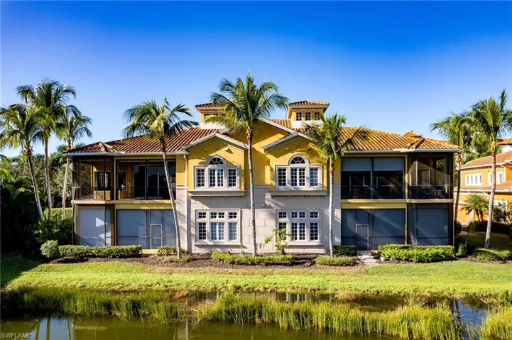 Back of house featuring a sunroom, a water view, and a tile roof