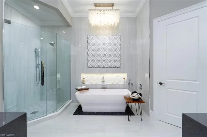 Bathroom with crown molding, a freestanding bath, a stall shower, tile patterned flooring, and a chandelier