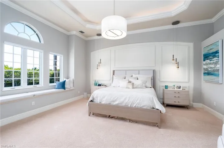 Carpeted bedroom with a raised ceiling and ornamental molding