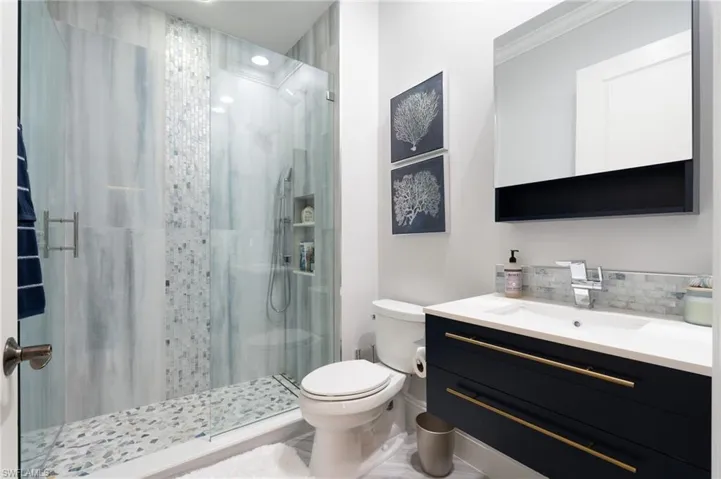 Full bathroom featuring a stall shower, vanity, and tasteful backsplash
