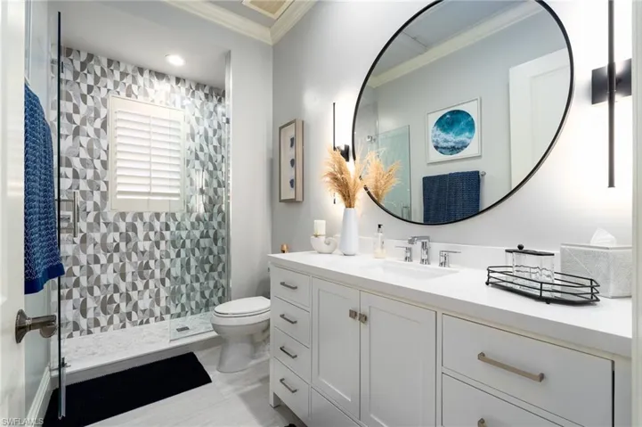 Full bathroom featuring vanity, a tile shower, and crown molding