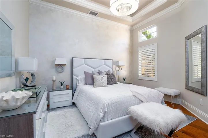 Bedroom featuring ornamental molding, wood finished floors, and a chandelier