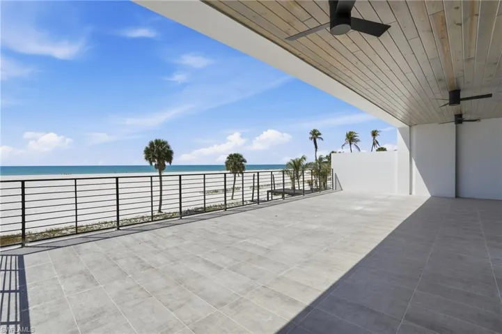 View of patio / terrace with a ceiling fan and view of water and beach