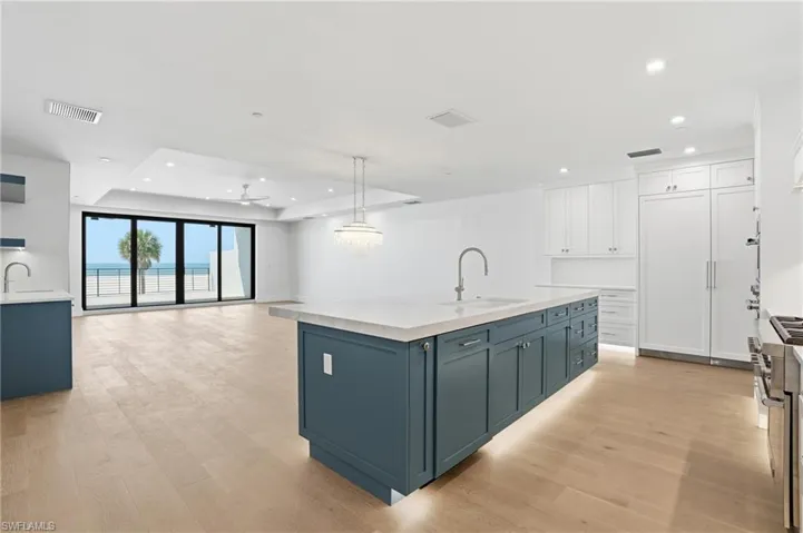 Kitchen with open floor plan, dual tone cabinetry, high end range, an island with sink, and light wood-style floors