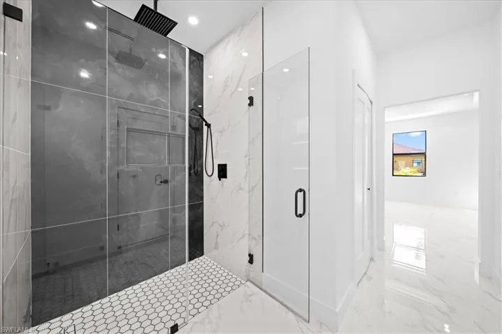 Bathroom featuring a marble finish shower, light marble finish flooring, and recessed lighting