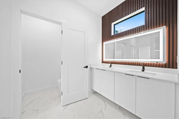 Bathroom featuring double vanity and light marble finish flooring