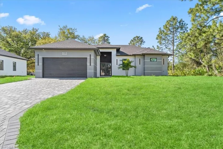 View of front of property with stucco siding, a front lawn, decorative driveway, and an attached garage