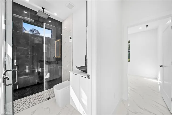 Full bathroom featuring vanity, light marble finish flooring, a marble finish shower, and recessed lighting