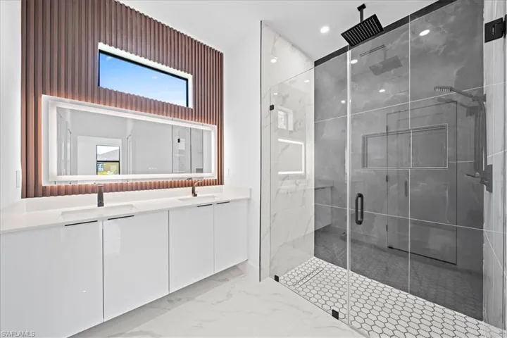 Bathroom with double vanity, a marble finish shower, light marble finish flooring, and recessed lighting