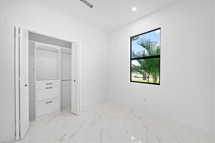Unfurnished bedroom featuring a closet, recessed lighting, and light marble finish floors