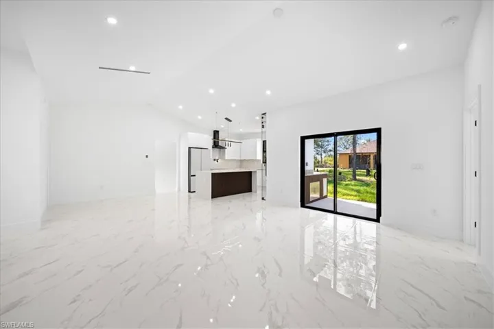 Unfurnished living room featuring recessed lighting, lofted ceiling, and light marble finish floors