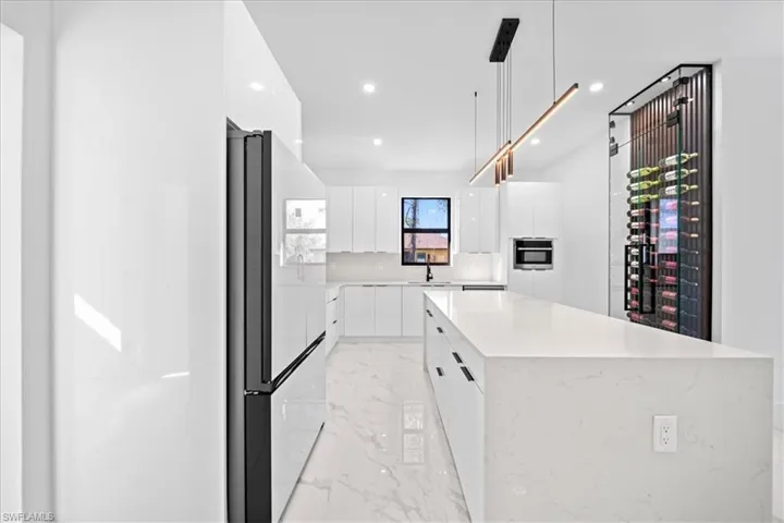 Kitchen featuring modern cabinets, freestanding refrigerator, a kitchen island, white cabinetry, and pendant lighting