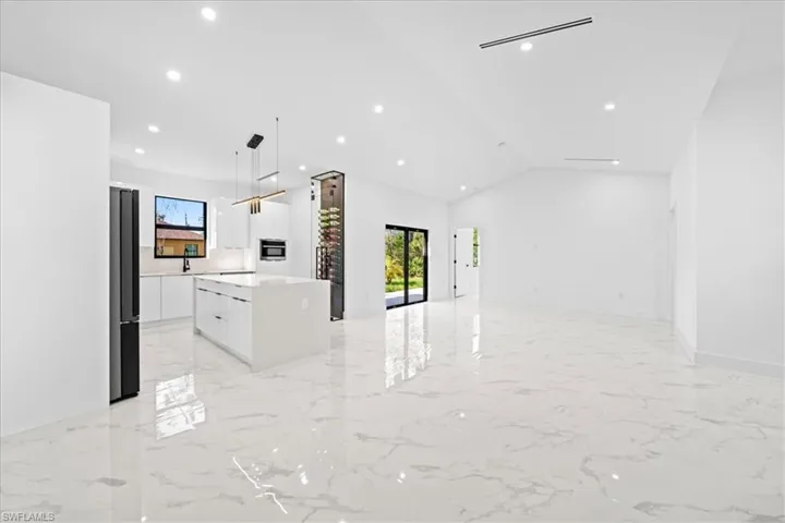 Kitchen with modern cabinets, a center island, white cabinets, plenty of natural light, and vaulted ceiling