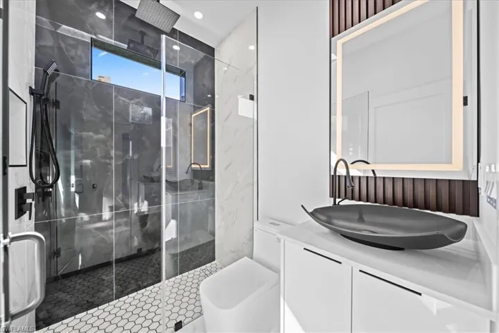 Bathroom featuring vanity, a marble finish shower, and recessed lighting