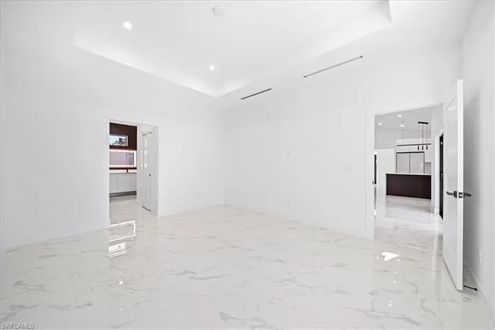 Unfurnished room featuring recessed lighting, a tray ceiling, and light marble finish flooring