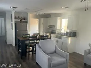 Kitchen featuring white cabinets, light countertops, stainless steel appliances, dark wood-type flooring, and rail lighting