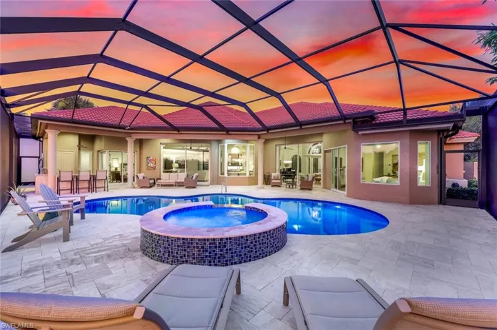 Pool at dusk featuring a patio, a pool with connected hot tub, a lanai, and a ceiling fan
