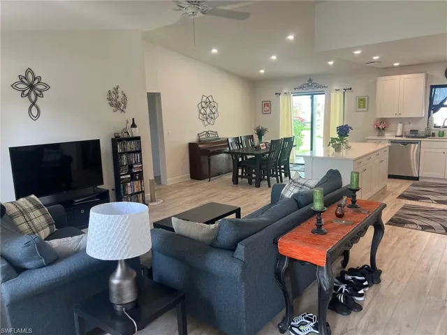 Living room with vaulted ceiling, light hardwood / wood-style flooring, and ceiling fan