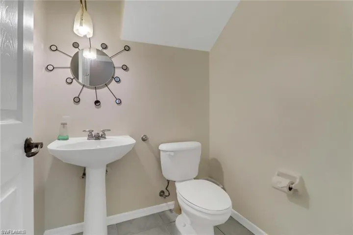 Bathroom with toilet, baseboards, a sink, and tile patterned floors