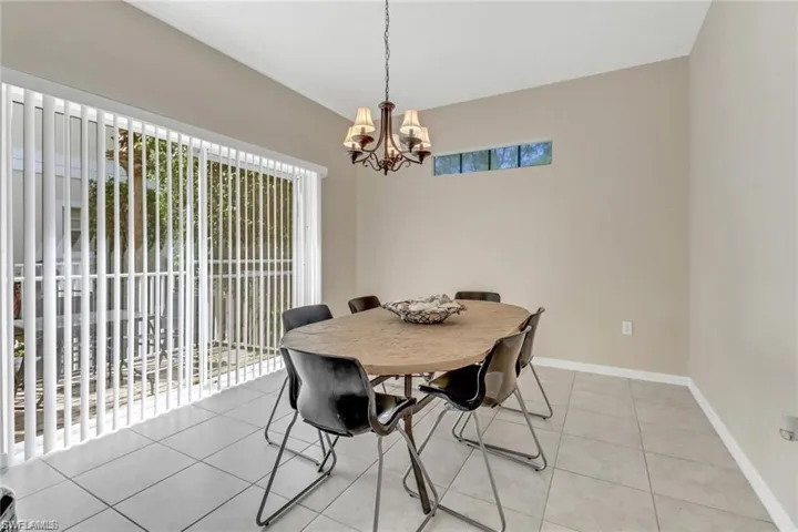Dining space with light tile patterned floors, baseboards, and an inviting chandelier