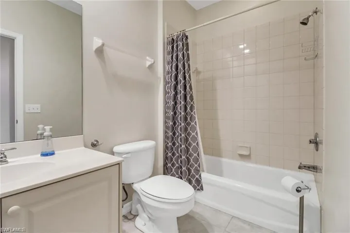 Full bath with shower / bath combo, tile patterned flooring, vanity, and toilet