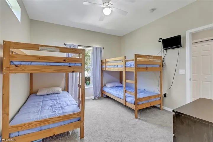 Bedroom with ceiling fan, baseboards, and light colored carpet