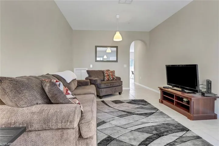 Living area featuring arched walkways, baseboards, and light tile patterned floors
