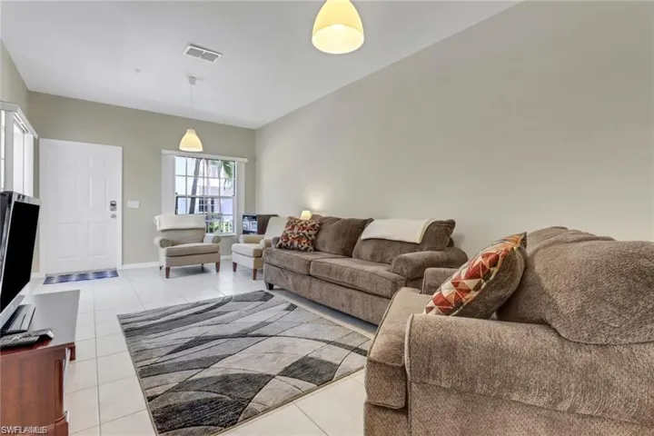 Living area with light tile patterned floors, baseboards, and visible vents