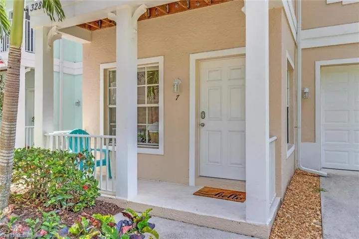 Entrance to property featuring a garage, covered porch, and stucco siding
