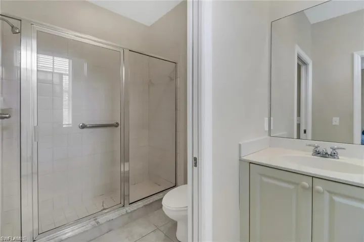 Full bathroom featuring tile patterned flooring, a shower stall, toilet, and vanity