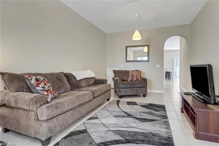 Living room with baseboards, arched walkways, and light tile patterned flooring