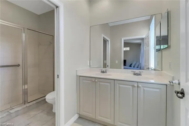 Bathroom with connected bathroom, a shower stall, a sink, and tile patterned floors