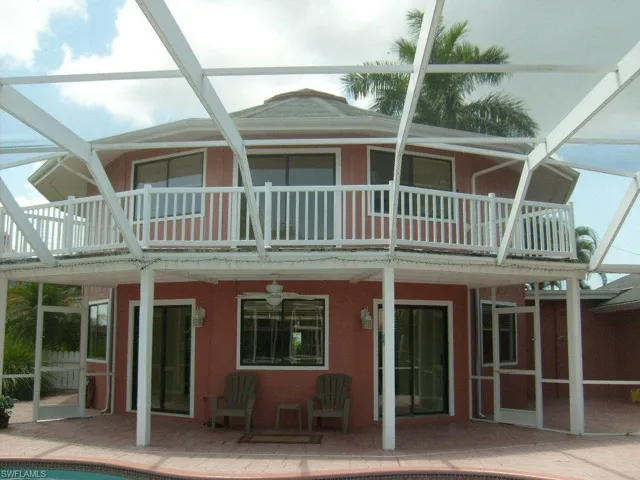 Back of property with ceiling fa, balcony and a lanai