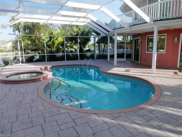View of pool with an in ground hot tub, a patio, and a lanai with patio canal view