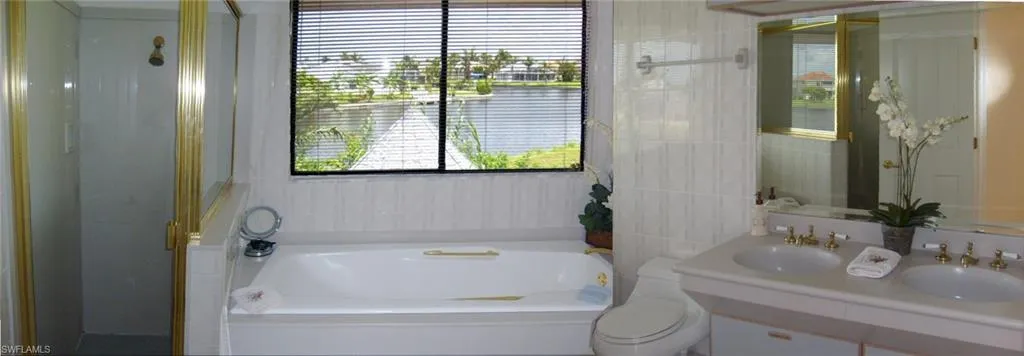 Master Bathroom with vanity, shower, toilet, a tub to relax in, and tile walls