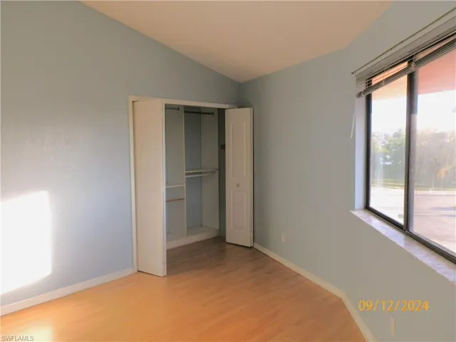 Unfurnished 2nd bedroom with access to exterior, a closet, vaulted ceiling, and light wood-type flooring