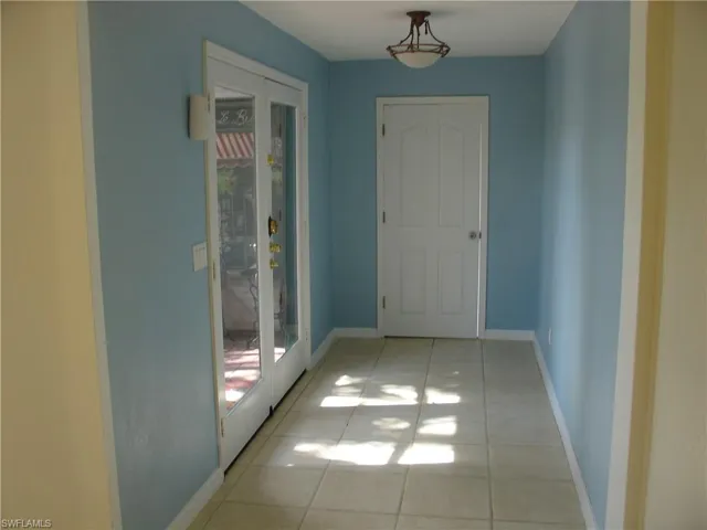 Hallway downstairs Corridor featuring light tile patterned flooring and french doors friendly colours