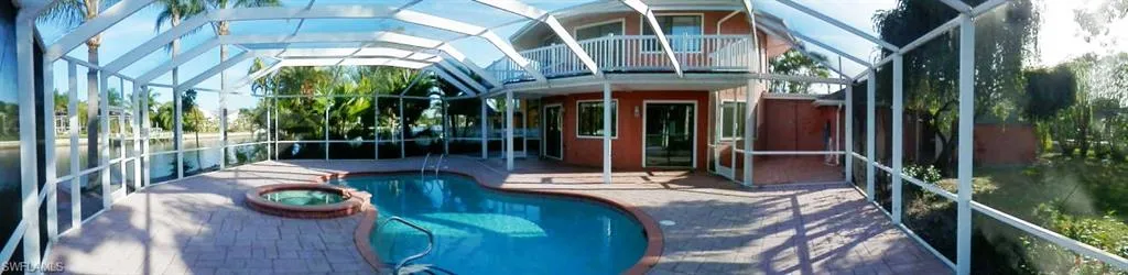 View of swimming pool featuring screen enclosure, an in ground hot tub, and a patio area