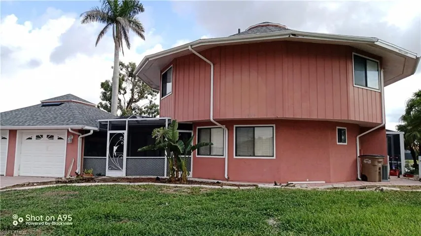 View of property featuring a garage and a front lawn