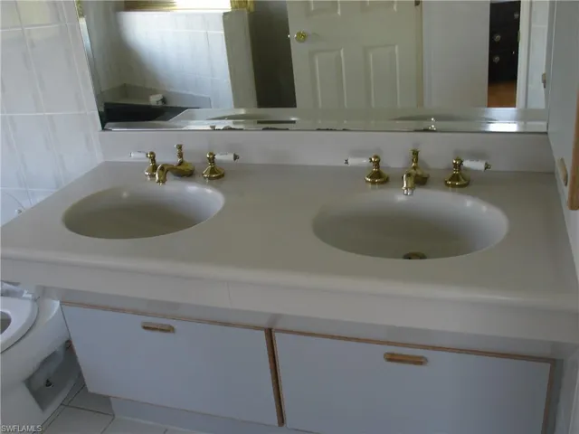 Master Bathroom with tile patterned flooring, double sink vanity, backsplash, and toilet