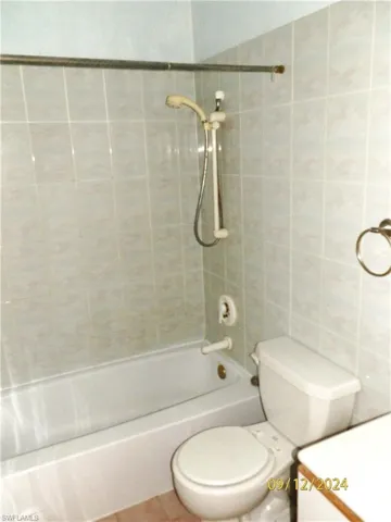 2nd Bathroom upstairs with tile patterned floors, tiled shower / bath combo, toilet, and tile walls
