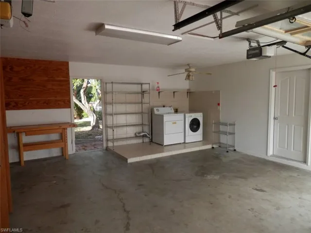 Garage with ceiling fan, a garage door opener, and washing machine and clothes dryer