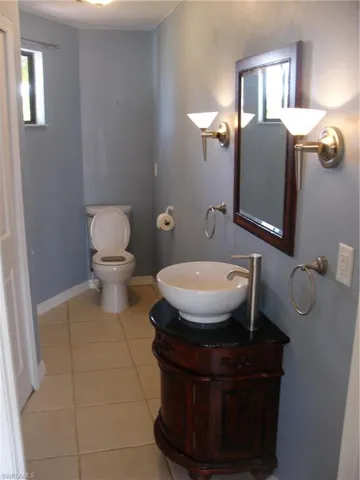Guest Bathroom down stairs featuring tile patterned flooring, vanity, and toilet