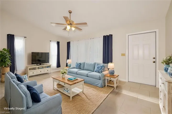 Living room featuring lofted ceiling, light tile patterned floors, and ceiling fan
