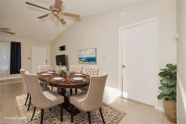 Dining space featuring light tile patterned flooring, ceiling fan, and lofted ceiling