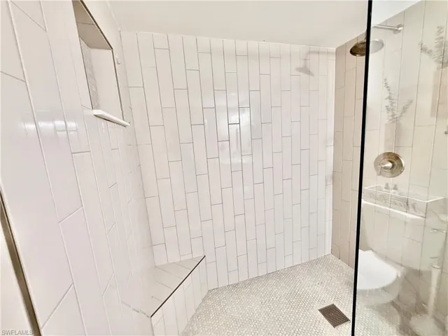Large tiled shower with frameless glass door.
